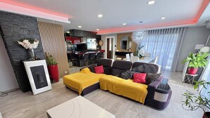 Ein modernes Wohnzimmer mit einer Eckcouch, einem Couchtisch und einem Essbereich im Hintergrund.