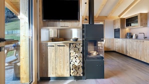 A modern kitchen with wooden cabinetry, a built-in TV, and a black refrigerator. - Chalet Hugo with Mountain Views, Shared Pool, and Wi-Fi (Vöran)