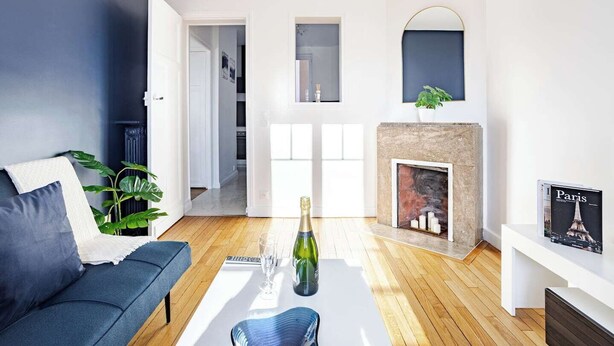 A modern living room with a dark blue sofa, a white coffee table, and a fireplace. - Elegance and comfort at the gateway to Paris (Aulnay-sous-Bois)