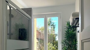 A compact laundry room with a washing machine, a drying rack, and a window providing a view of greenery outside. - Elegance and comfort at the gateway to Paris (Aulnay-sous-Bois)