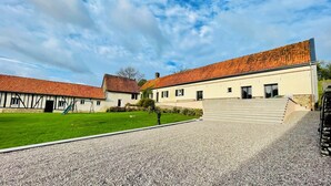 A courtyard with a gravel path, a green lawn, and a building with a red-tiled roof. - Group Gîte: Domaine de la Vacquerie (Alette)