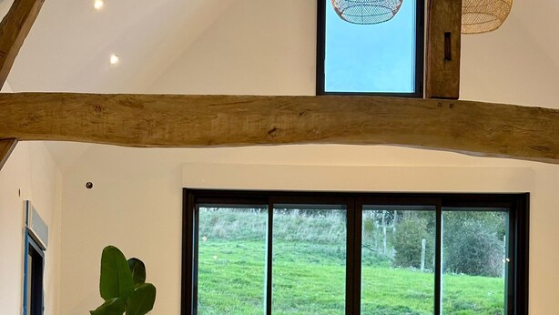 A person in a swimming pool with a view of a grassy landscape through large windows. - Group Gîte: Domaine de la Vacquerie (Alette)