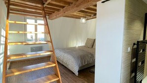A loft bedroom with a wooden staircase, a bed, and a view of the outdoors. - Group Gîte: Domaine de la Vacquerie (Alette)