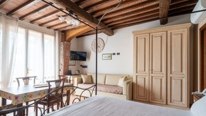 A room with a bed, a dining table with chairs, a sofa, and a wardrobe. - Hotiday Relais Costa degli Etruschi (Rosignano Marittimo)