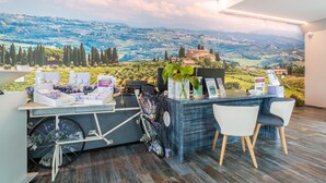 A reception desk with a scenic view of rolling hills and a castle, a bicycle, and a plant. - Hotiday Relais Costa degli Etruschi (Rosignano Marittimo)