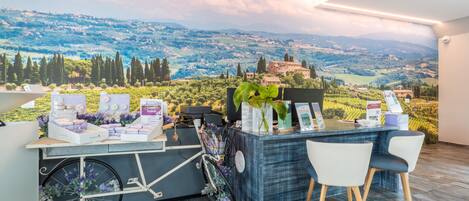 A reception desk with a scenic view of rolling hills and a castle, a bicycle, and a plant.
