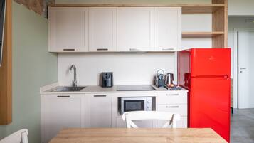 A kitchen with white cabinets, a red refrigerator, a microwave, and a coffee maker.