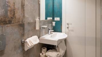 A bathroom with a bidet, a sink, a mirror, and a towel rack.
