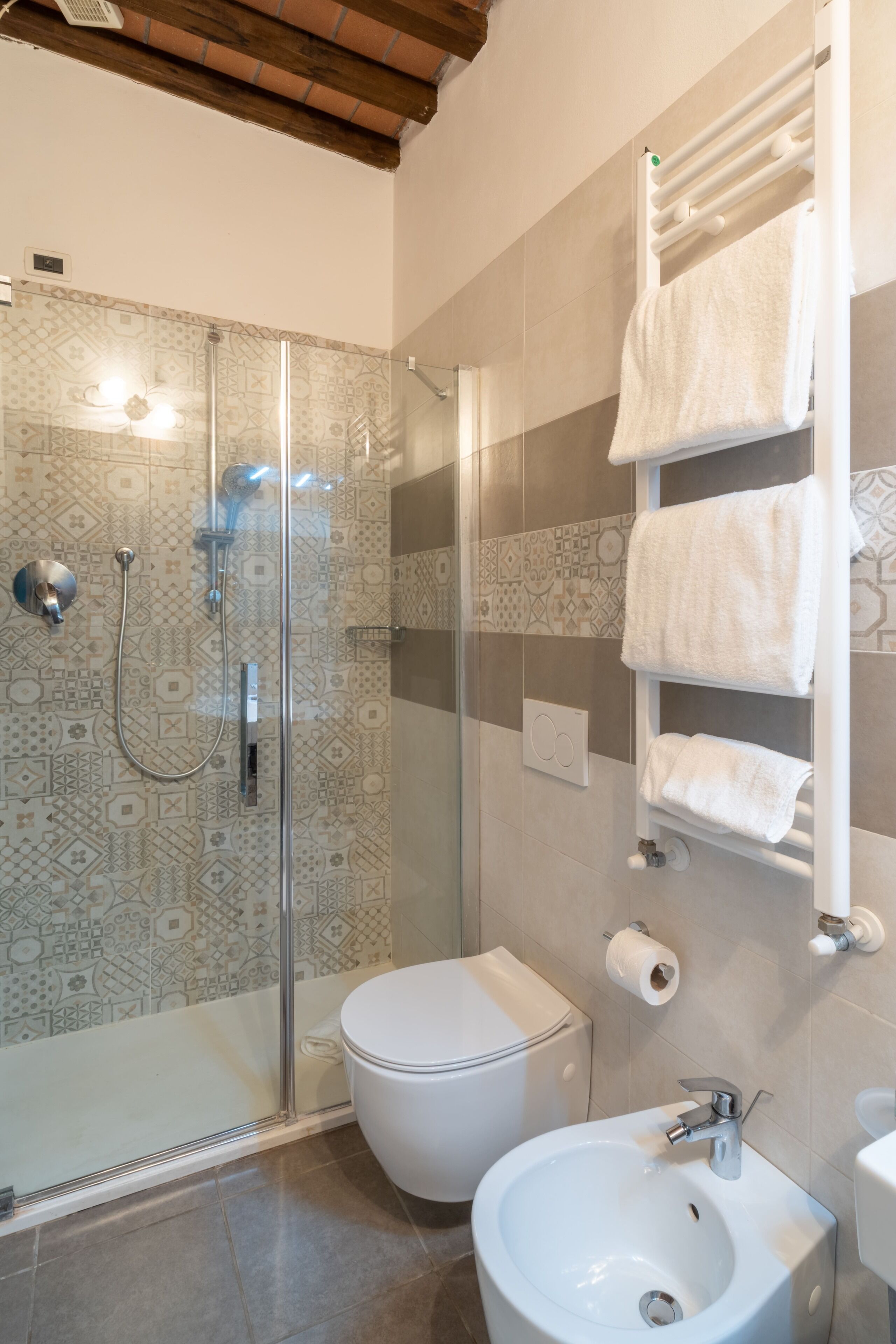 A bathroom with a glass-enclosed shower, a toilet, and a sink.
