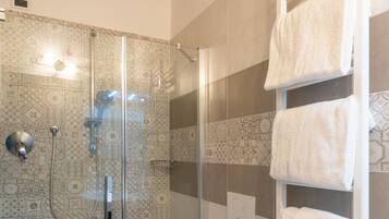 A bathroom with a glass-enclosed shower, a toilet, and a sink.