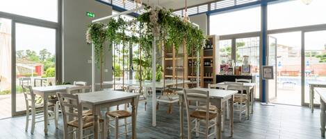 A restaurant with white tables and chairs, a central floral arrangement, and large windows.