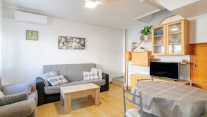 A living room with a sofa, a coffee table, a TV, a cabinet, and a ceiling fan. - Bungalow 'Fontilles 3 En Santa Pola' with Private Terrace, Wi-Fi and Air Conditioning (Santa Pola)