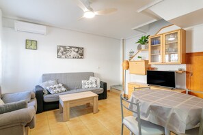 A living room with a sofa, a coffee table, a TV, a cabinet, and a ceiling fan. - Bungalow 'Fontilles 3 En Santa Pola' with Private Terrace, Wi-Fi and Air Conditioning (Santa Pola)