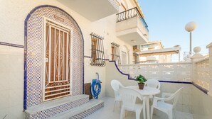 A balcony with white chairs, a table, and a potted plant. - Bungalow 'Fontilles 3 En Santa Pola' with Private Terrace, Wi-Fi and Air Conditioning (Santa Pola)