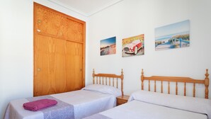 A room with two single beds, a wooden wardrobe, and three wall-mounted pictures. - Bungalow 'Fontilles 3 En Santa Pola' with Private Terrace, Wi-Fi and Air Conditioning (Santa Pola)