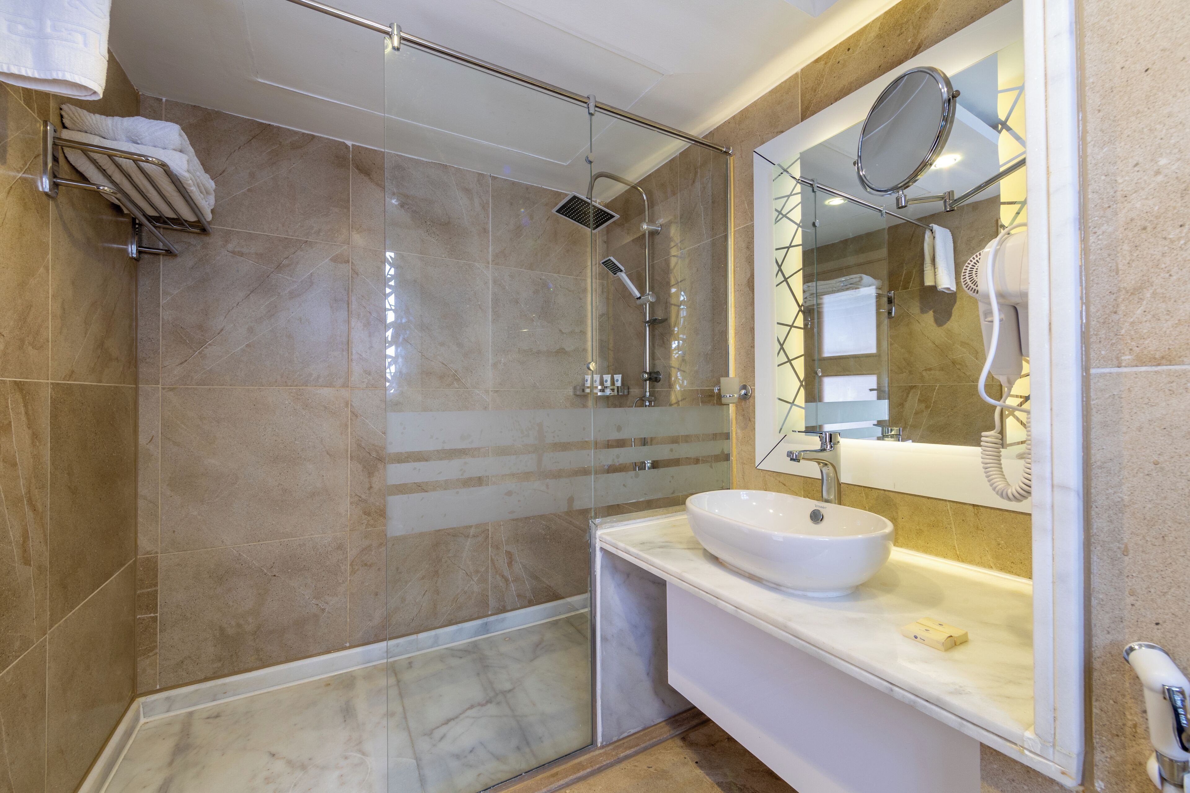 A modern bathroom with a glass-enclosed shower, a white sink, and a large mirror.