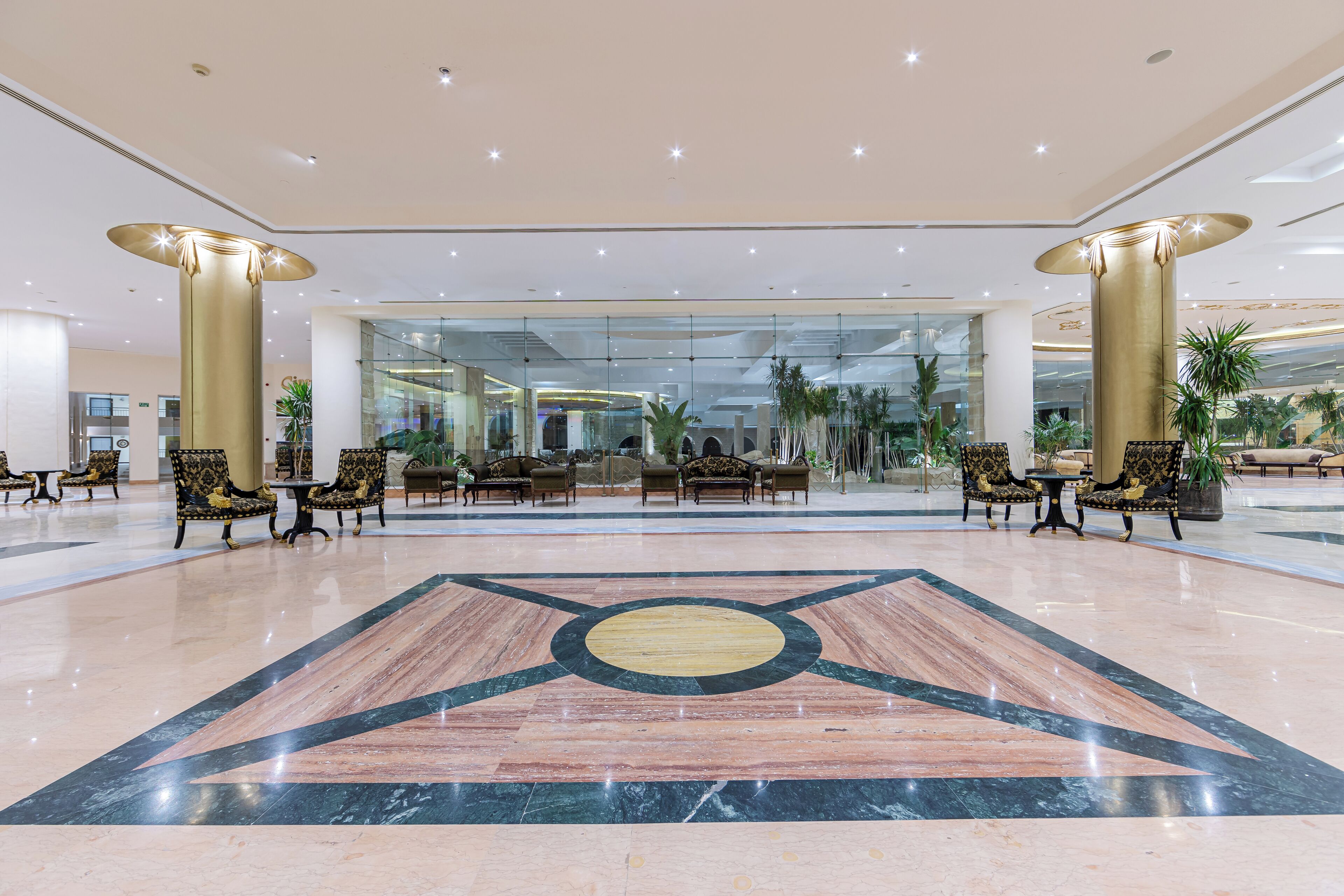 A spacious lobby with a marble floor, large columns, and seating areas with patterned chairs.