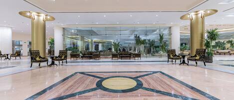 A spacious lobby with a marble floor, large columns, and seating areas with patterned chairs.