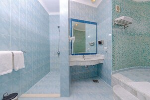 Un baño con azulejos azules, un lavabo, un espejo, una ducha y una bañera.