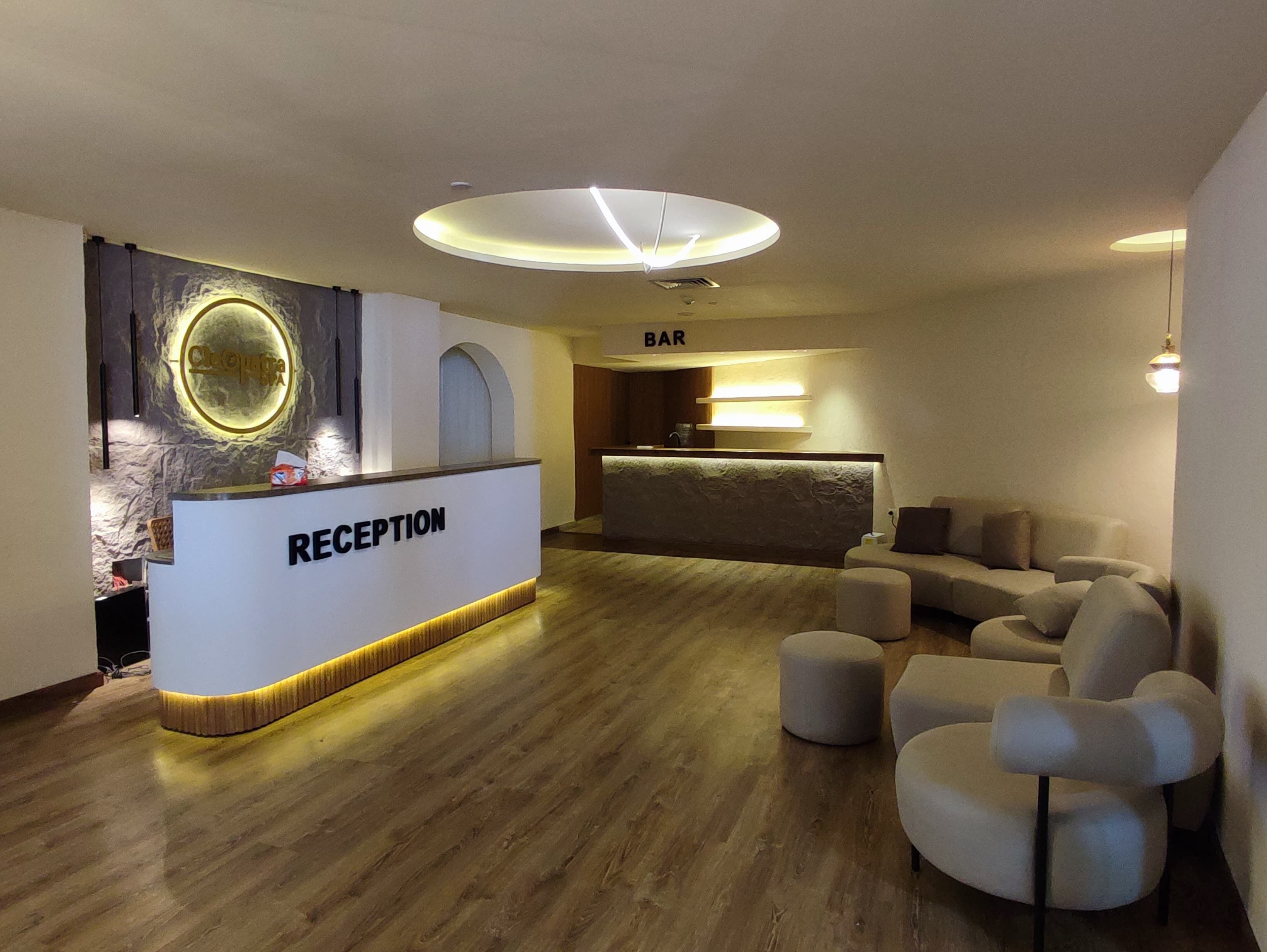 Ein Empfangsbereich mit einer Rezeption, einer Bar und einer Sitzecke mit Poufs.