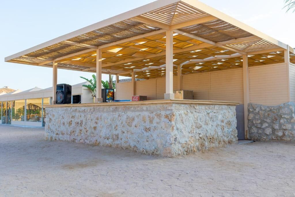 A covered outdoor area with a stone wall, a speaker, and a Coca-Cola cooler.