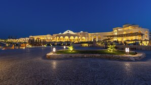 Un hotel grande e iluminado con un patio central, asientos al aire libre y una piscina.