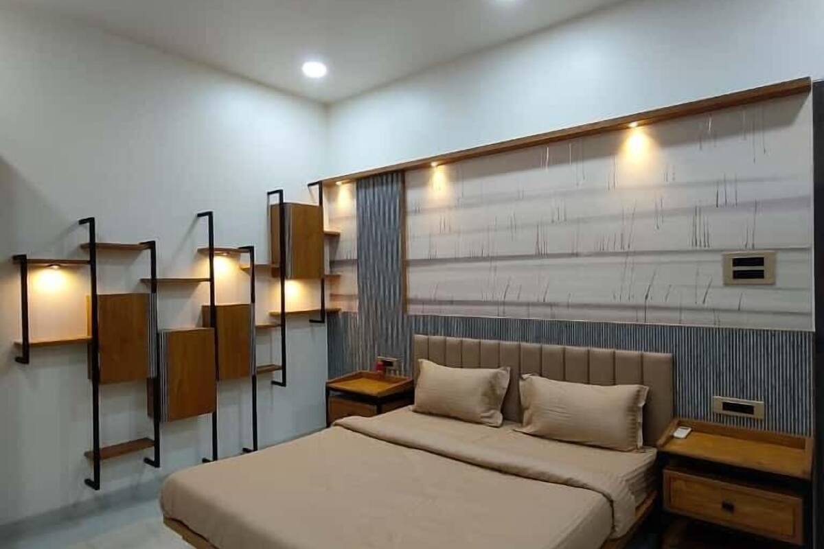 Un dormitorio moderno con una cama grande, mesitas de noche de madera, un ventilador de techo e iluminación empotrada.