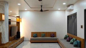 Un salon moderne doté d’un téléviseur à écran plat, d’une console en bois, d’un canapé avec des coussins, d’un ventilateur de plafond et d’un éclairage encastré.