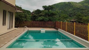 Une piscine rectangulaire dotée d’une terrasse en bois et entourée d’une clôture en bois.