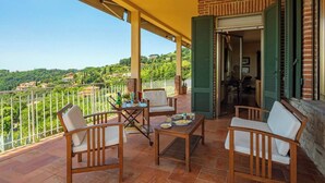 Ein Balkon mit Holzmöbeln, einem Tisch und Blick auf eine grüne Landschaft.