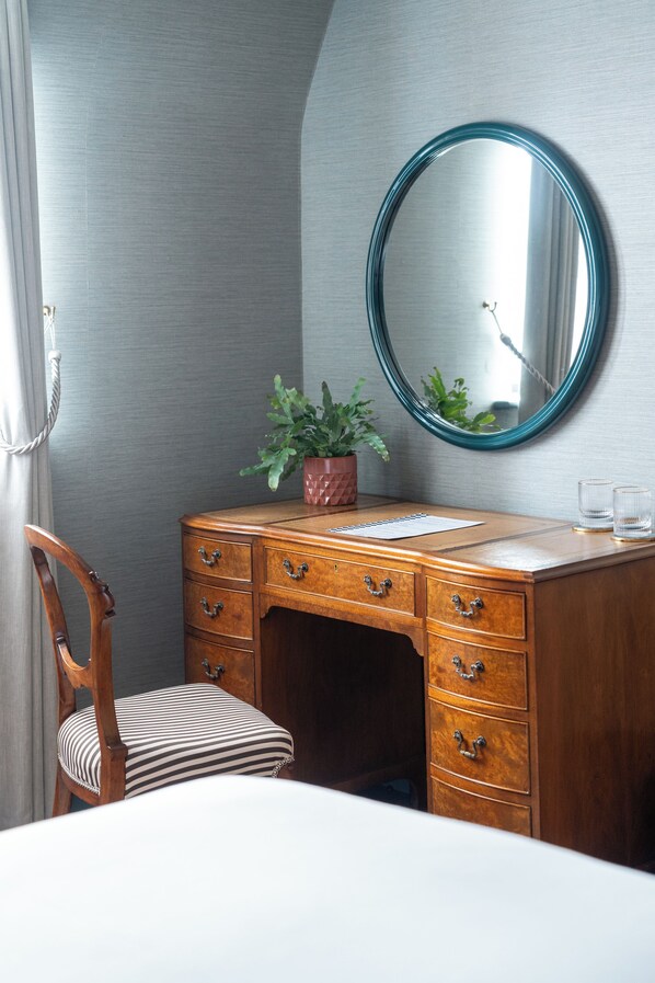 A wooden dresser with drawers, a mirror, and a potted plant. - The Hat Maker Boutique Hotel (Dungarvan)