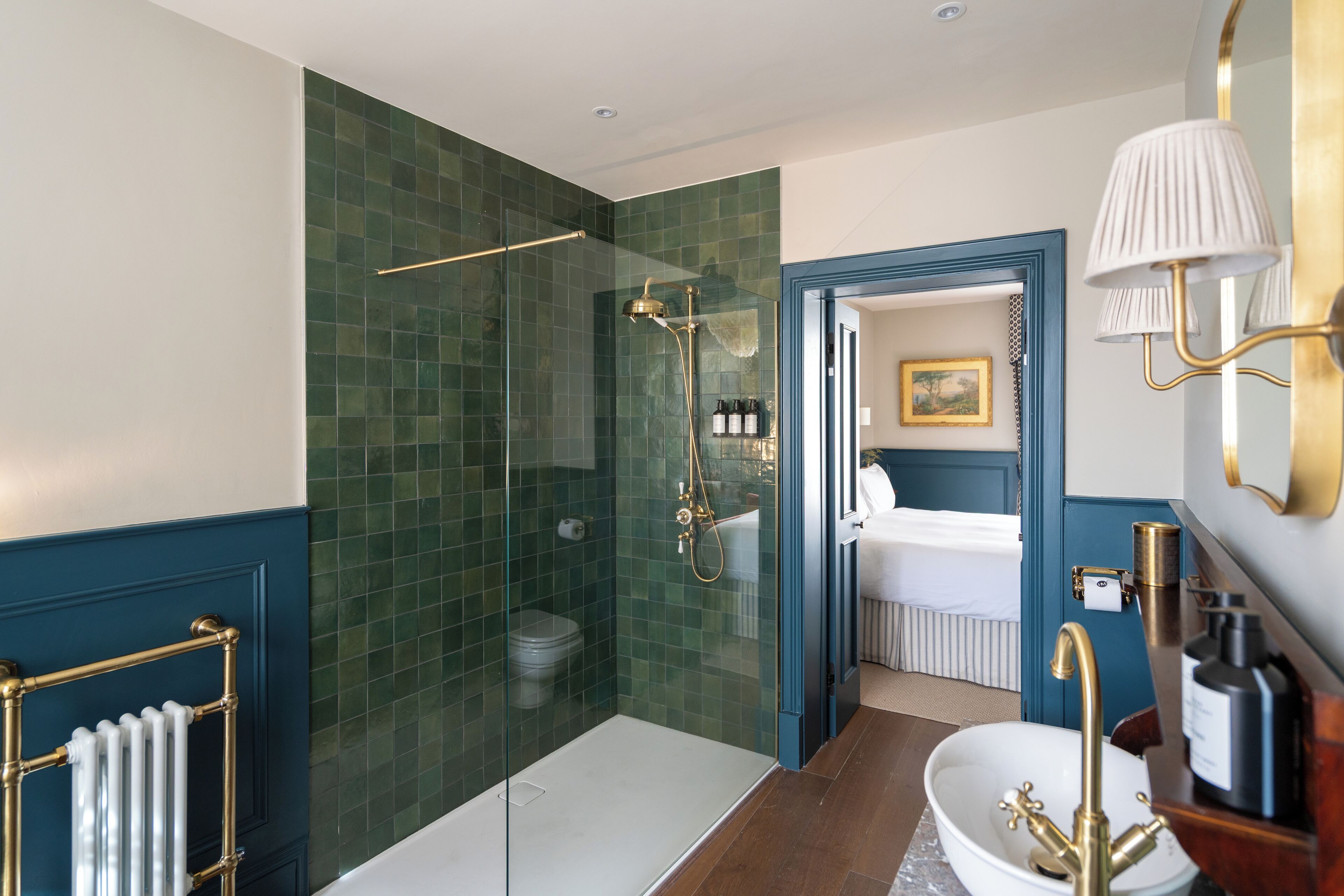 A modern bathroom with a glass-enclosed shower, a white bathtub, and a blue accent wall.