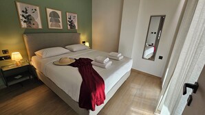 Une chambre d’hôtel avec un lit, une table de chevet, une lampe, un chapeau et des serviettes.