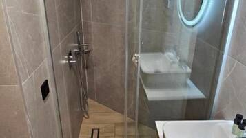 A modern bathroom with a glass-enclosed shower, a white sink, and a wooden vanity.