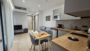 Une cuisine moderne équipée d’un four à micro-ondes, d’un évier et d’une machine à café. Un coin repas avec une table et des chaises est également disponible.