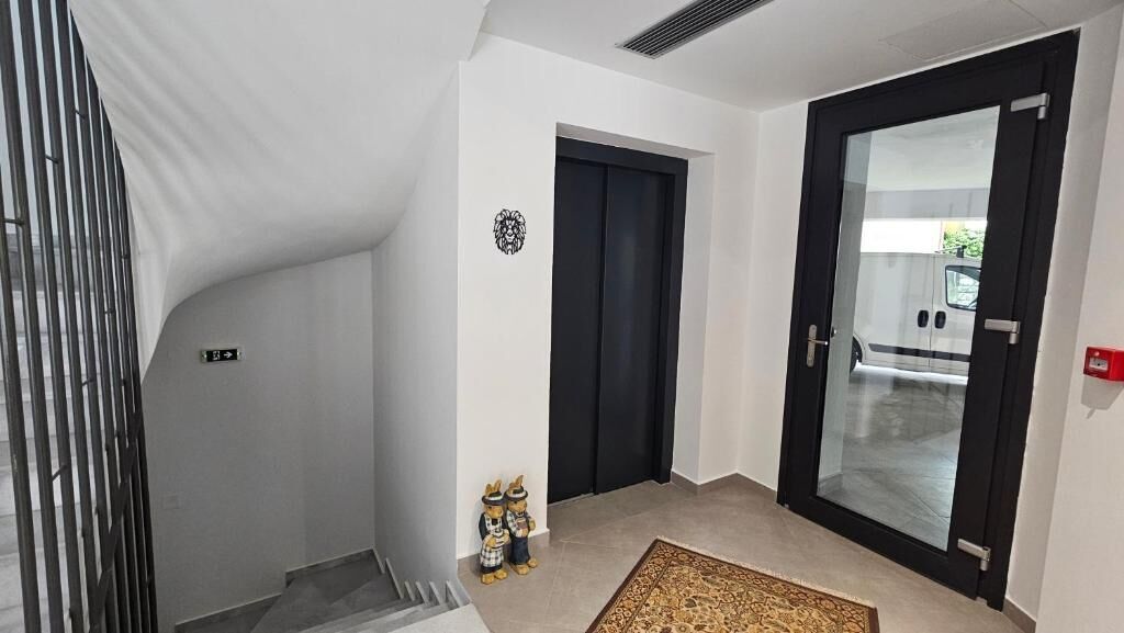 Un pasillo con una puerta negra, un detalle decorativo y una alfombra.