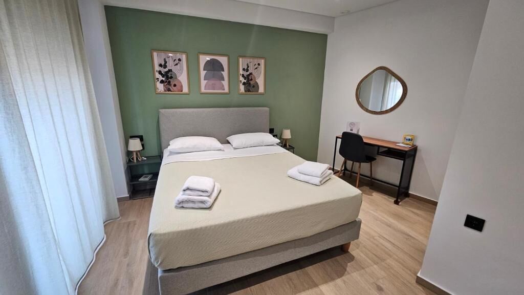 A bedroom with a bed, bedside tables, a desk, and a mirror.