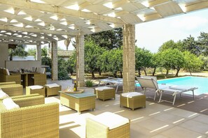 An outdoor patio area with wicker furniture, a pool, and a pergola structure. - Villa Adriana with private pool - My Rental Homes (Marsala)