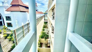 A multi-story building with balconies, a red-roofed structure in the background, and a clear sky. - Horison Kuta Bali (Kuta)