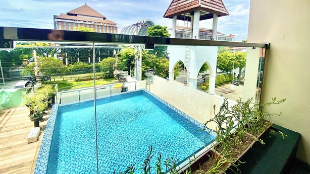 A rooftop swimming pool with a view of a church and surrounding buildings. - Horison Kuta Bali (Kuta)