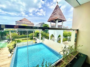 A rooftop swimming pool with a view of a church and surrounding buildings. - Horison Kuta Bali (Kuta)