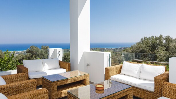 A balcony with wicker furniture, a glass table, and a view of the sea. - Luxurious Villa Rizes - with Private Pool (Maroulas)