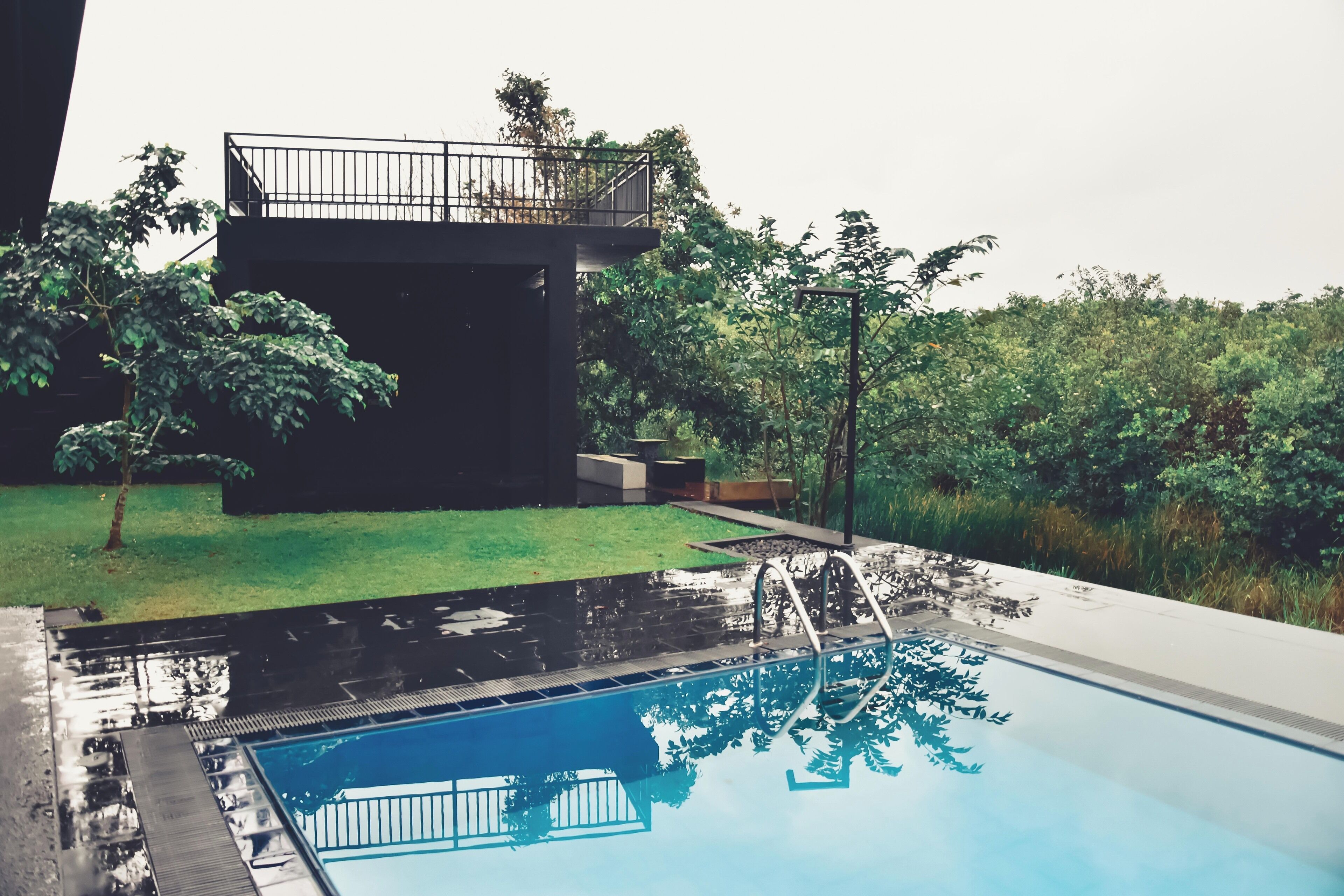 A swimming pool with a clear view of the surrounding greenery and a modern building structure.