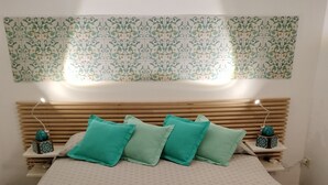 Une chambre à coucher comprenant un lit, deux tables de chevet, une tête de lit et un luminaire fixé au mur.