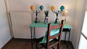 Un coin repas comprenant une table, des chaises, un radiateur, une plante en pot et une lampe.