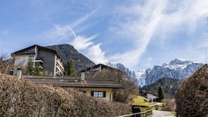 A mountain house with a sloped roof, a balcony, and a view of snow-capped mountains. - Vacation apartment Bergkristall with Watzmann view (Berchtesgaden)