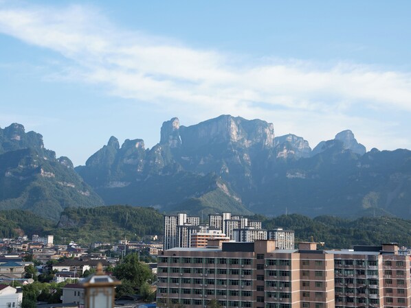 A cityscape with modern buildings and a mountain range in the background. - Patio Spring Holiday Inn (Zhangjiajie)