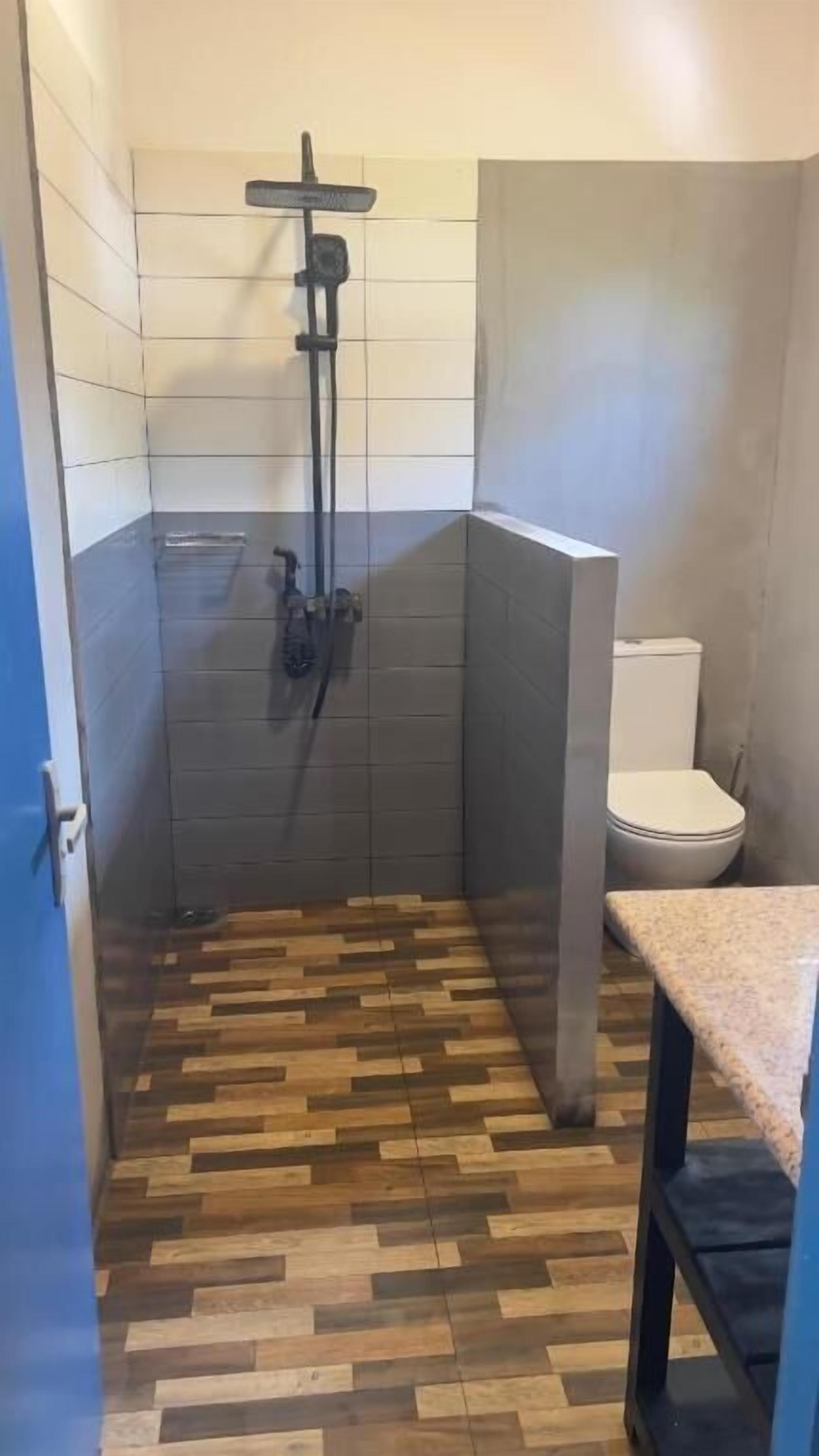 Un baño pequeño con ducha, inodoro y suelo de madera.