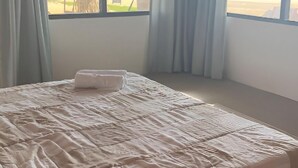 A bedroom with a bed, large windows, and a view of the beach. - Villa ArthurCC (Hikkaduwa)