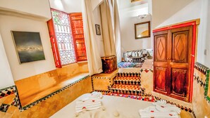 A room with a bed, a small table, a chair, and a decorative wall.